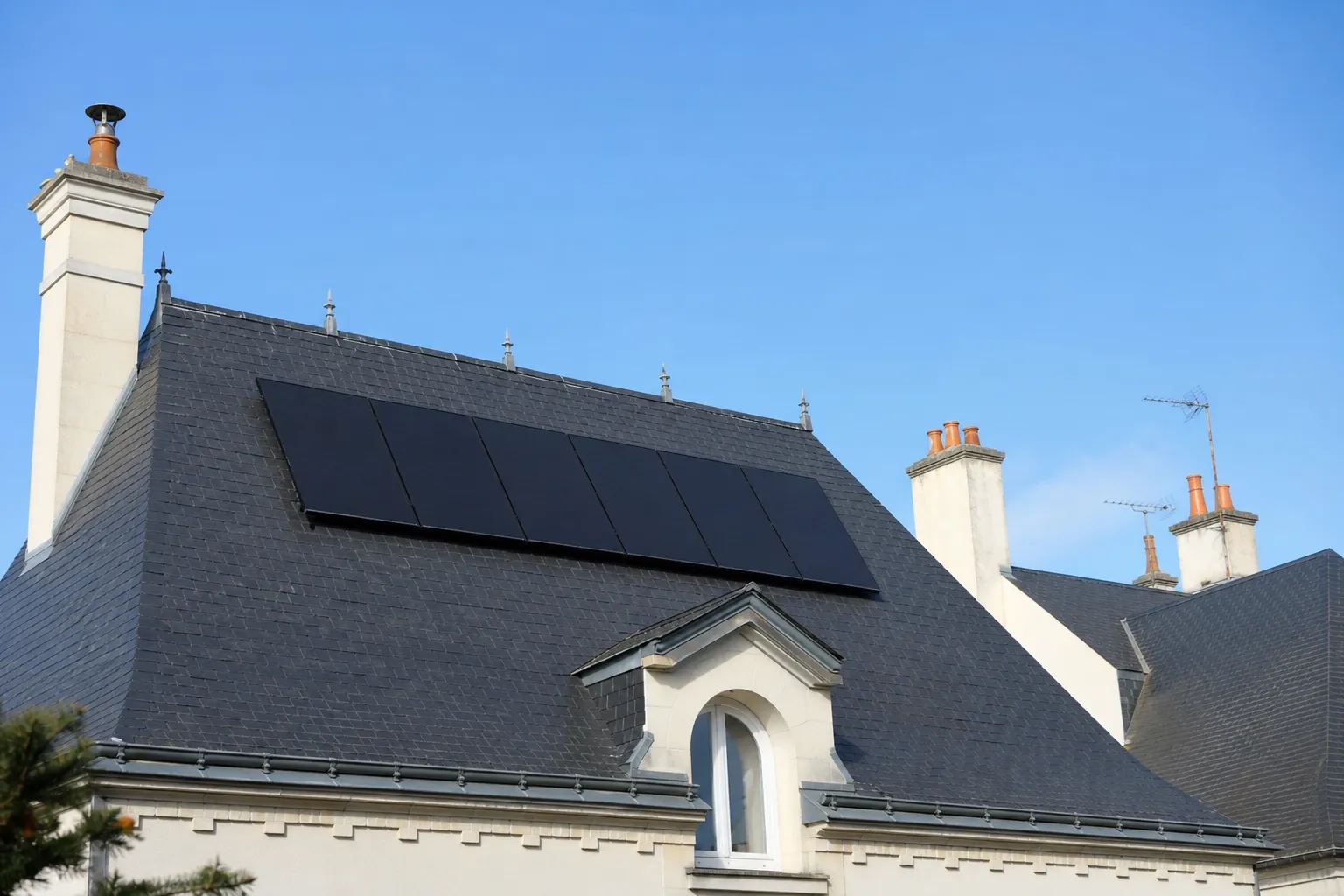Toiture d’ardoise angevine dont le pan sud porte une rangée de panneaux solaires posée au ras de la couverture