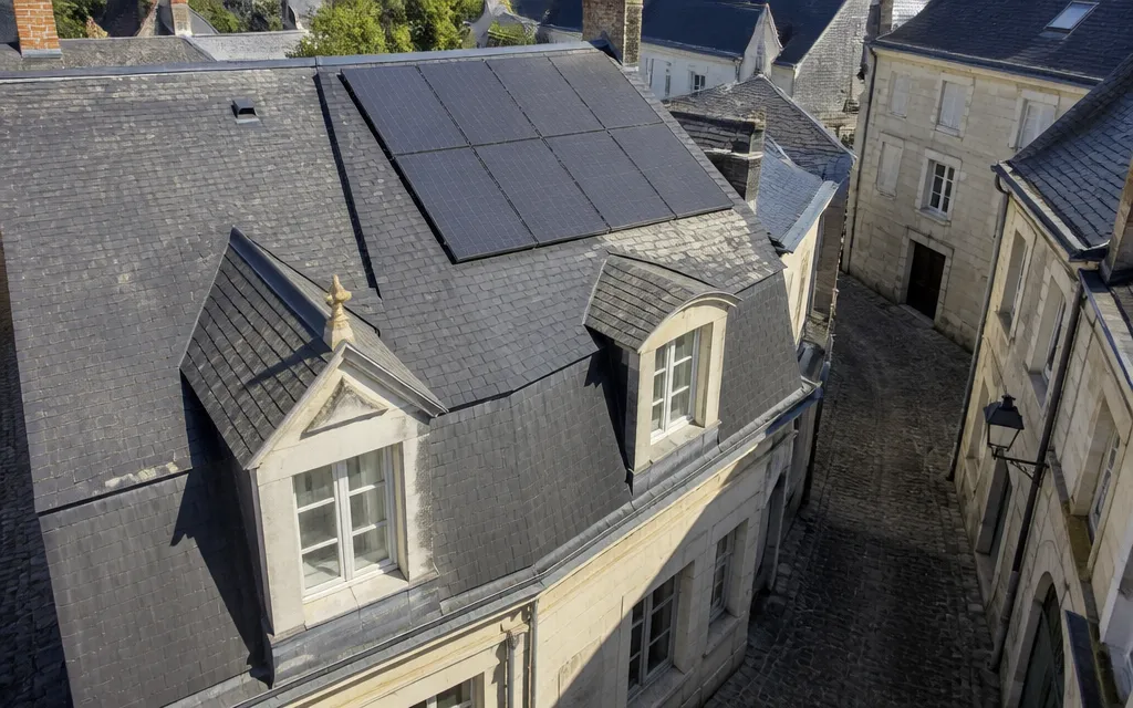 Toiture d’ardoise à forte pente d’une maison de ville angevine avec panneaux solaires intégrés